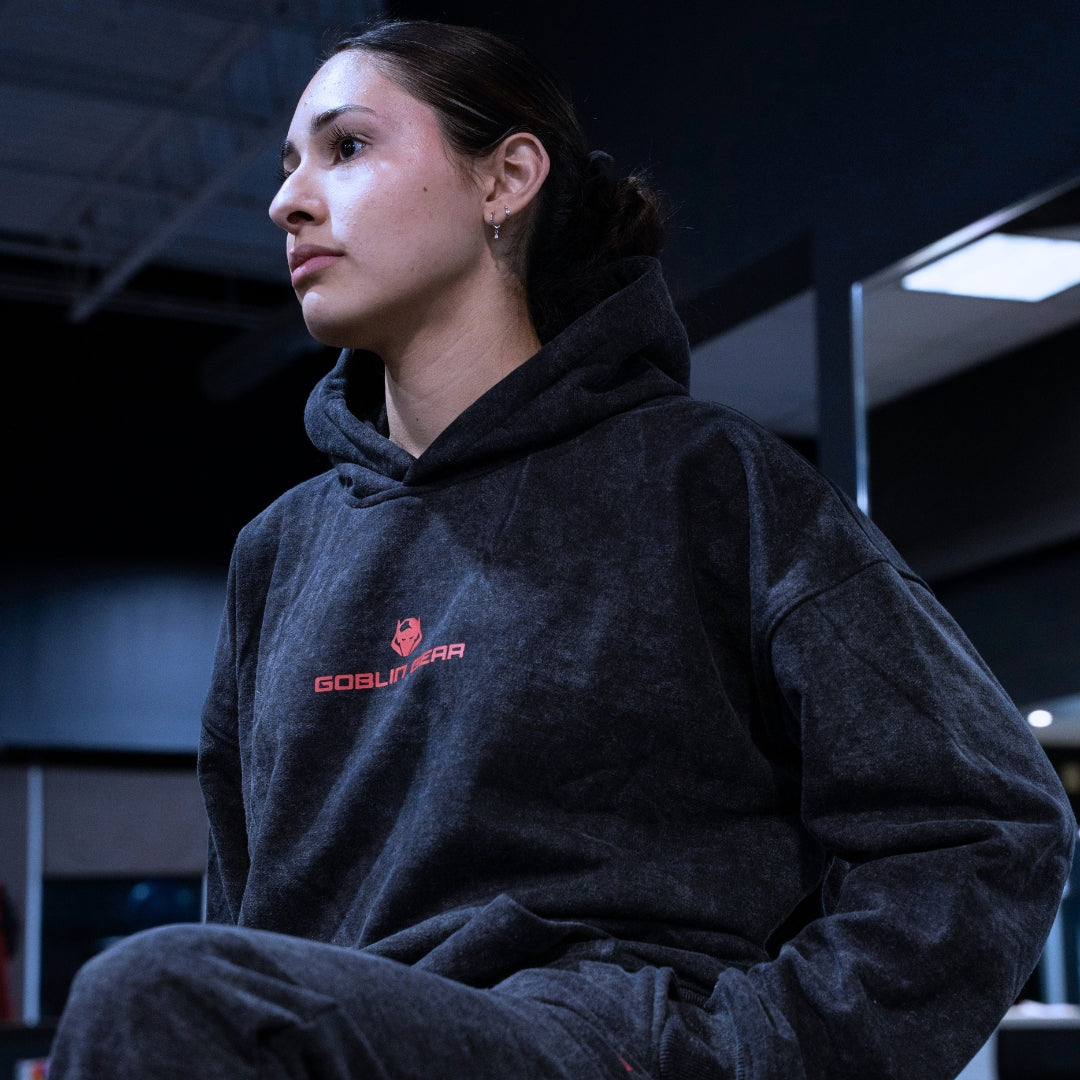 Goblin Gear Acid Wash Hoodie – person wearing a dark hoodie with a logo in an indoor setting
