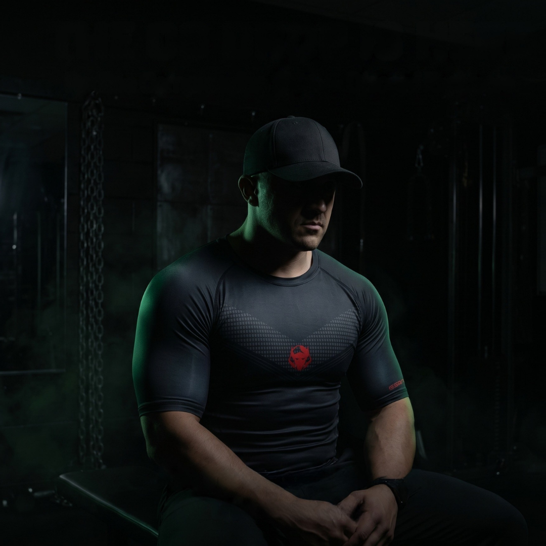 Goblin Gear Redline Compression Tee – person wearing a dark t-shirt with a red logo in a dimly lit room