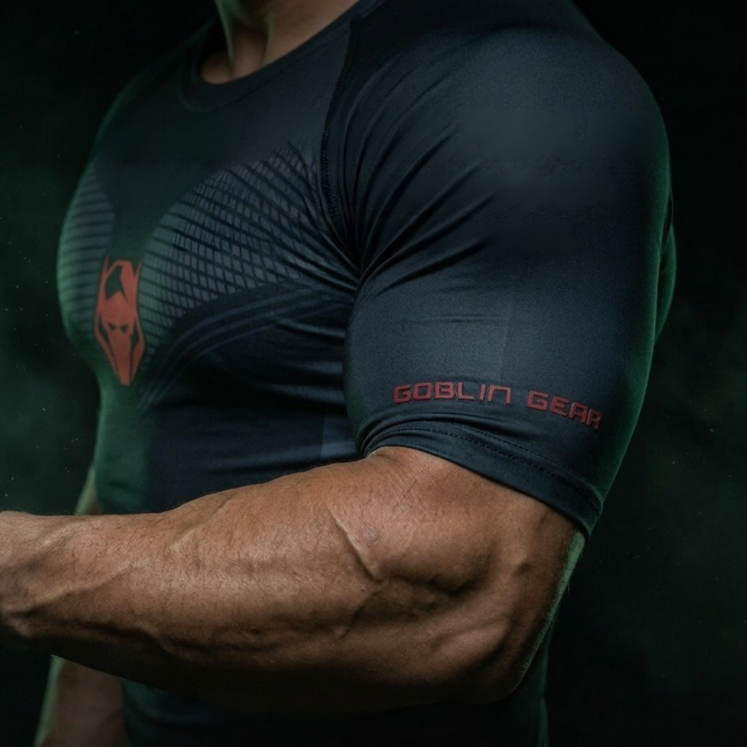 Goblin Gear Redline Compression Tee – person in a dark green athletic shirt with Goblin Gear branding, flexing