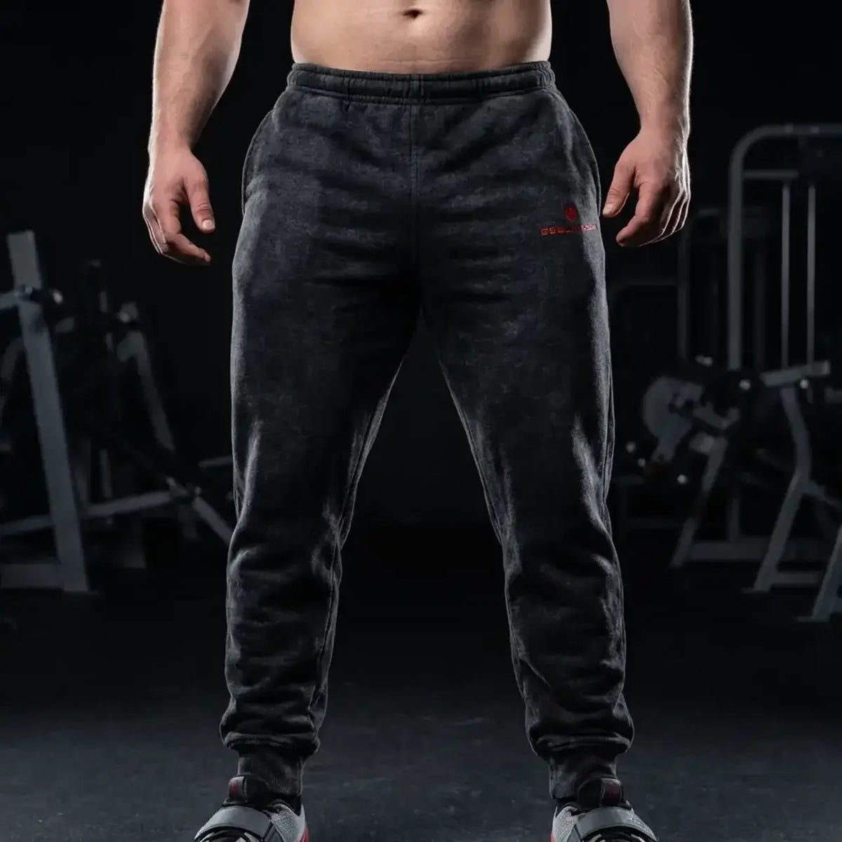 Goblin Gear Acid Wash Sweat Pants – person wearing dark gray sweatpants with a logo in a gym setting